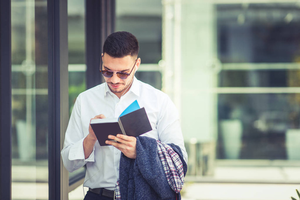Modern young businessman is standing and reading a book - Foto, Imagen