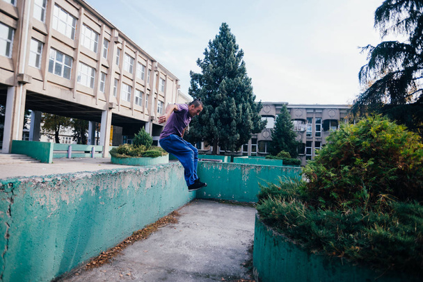 Strongman while training parkour jumping over the concrete wall  - Fotó, kép