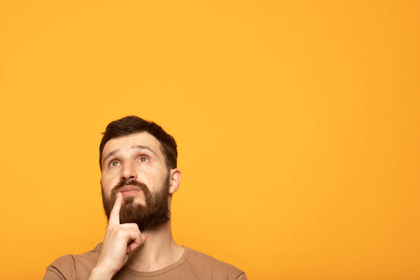 young man thinking about things on yellow background - Photo, image