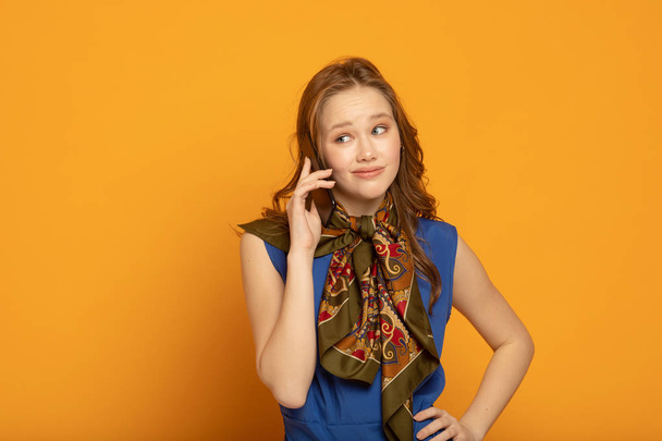 Portrait of young woman 20s in casual clothes speaking on smartphone while standing isolated over yellow background - Foto, Imagem