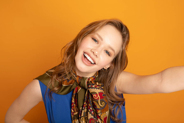 Selfie tijd! Aantrekkelijke jonge vrouw in casual slijtage het maken van selfie door haar Smartphone en glimlachen terwijl staan tegen gele achtergrond  - Foto, afbeelding