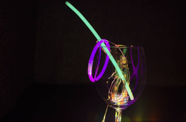 Blauwe en groene gloed stok op een wijn glas met kleurrijke licht re - Foto, afbeelding
