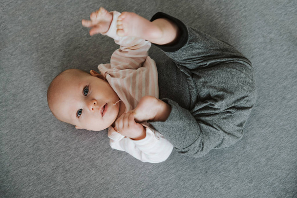 νεογέννητο τέντωμα των χεριών και των ποδιών στο πάτωμα, κορυφή θέα - Φωτογραφία, εικόνα