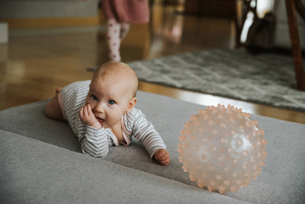newborn girl plays with a ball on the floor - Foto, imagen