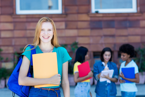 Британская студентка с рыжими волосами и группой студентов
 - Фото, изображение