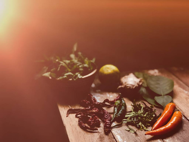 Preparation and cooking vegetables, basil leaves, kaffir lime leaves, lime and knife on table  - Фото, зображення