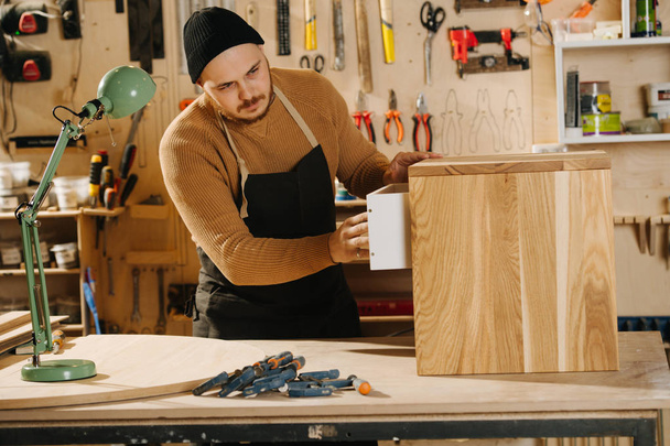 Carpenter is making furniture on order in a workshop. - Foto, afbeelding