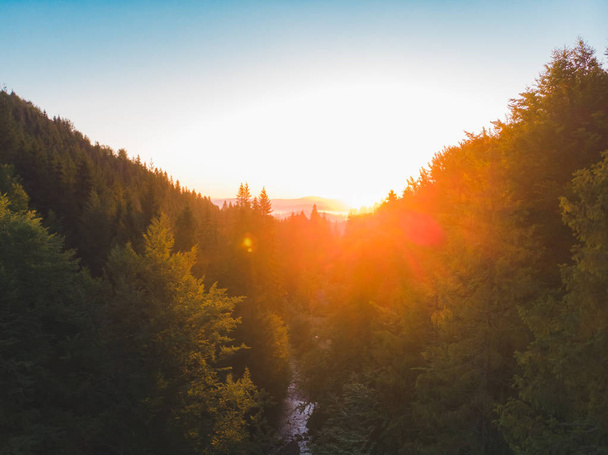 Αεροφωτογραφία του ηλιοβασίλεμα πάνω από τα βουνά με το δάσος και το ποτάμι - Φωτογραφία, εικόνα