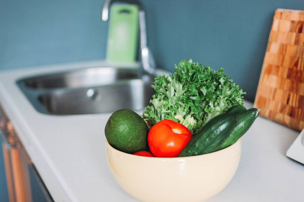 Saisons fraîches légumes concombres, tomate, légumes verts dans les plats sur la table de cuisine à la maison
 - Photo, image