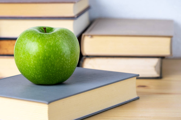 Bücher und grüner Apfel auf dem Holztisch - Foto, Bild