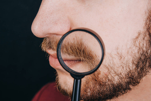beard under a magnifying glass. hairline on a man's face close up. portrait of a guy with a mustache - Foto, Imagen