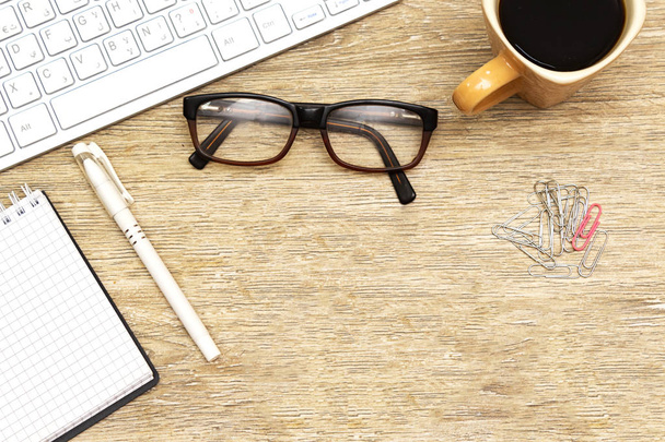 Flat lay foto de mesa de escritório com teclado, notebook, óculos e xícara de café, clipe de papel e caneta. vista superior
 - Foto, Imagem