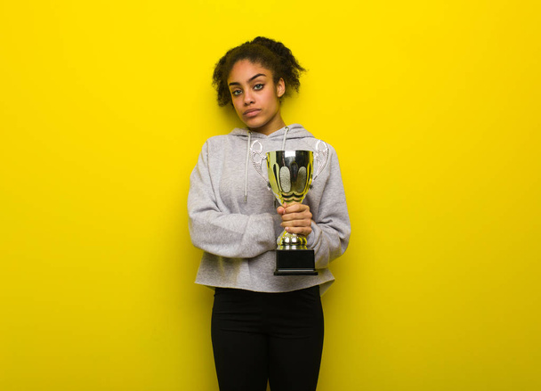 Young fitness black woman looking straight ahead. Holding a trophy. - Photo, Image