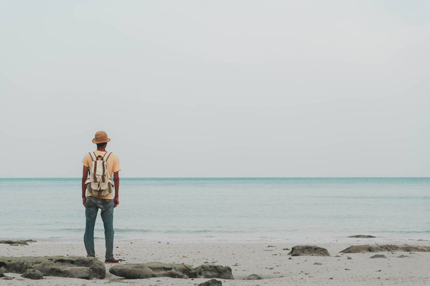 jovem com mochila em pé na praia e olhando para o horizonte do oceano. conceito para aventura e viagens mar em férias de verão e ao ar livre sozinho, mar sul da Tailândia, koh yao yai
 - Foto, Imagem