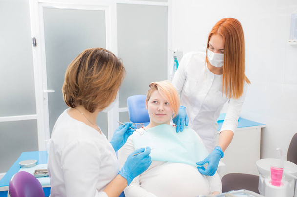 woman in the dentist's chair, the doctor adjusts the patient's head, the dental assistant - Foto, Imagen