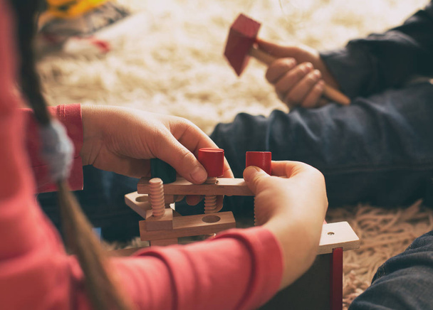Kinderen spelen met houten speelgoed op de vloer - Foto, afbeelding