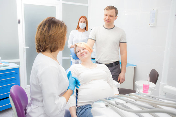 pregnant woman at the reception at the dentist, the husband  are present in the office. Dental treatment for pregnant women. - 写真・画像