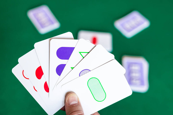 jugador sostiene Conjunto de cartas de juego sobre la mesa verde
 - Foto, Imagen