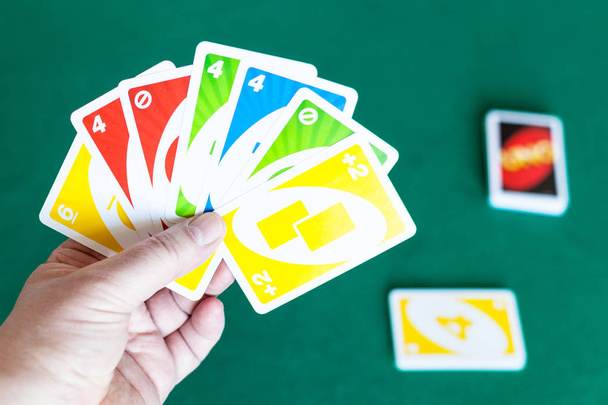 jugador sostiene UNO cartas de juego sobre la mesa verde
 - Foto, Imagen