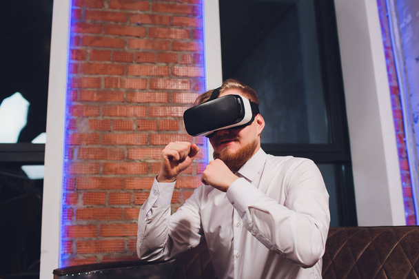 Closeup of male hand.Bearded young man wearing virtual reality goggles in modern coworking studio. Smartphone using with VR headset in office. - Foto, Imagem