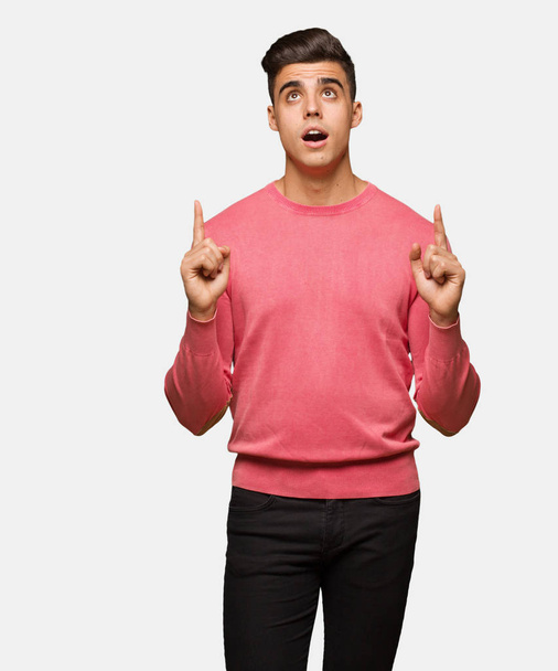 Young funny man surprised pointing up to show something - Photo, Image