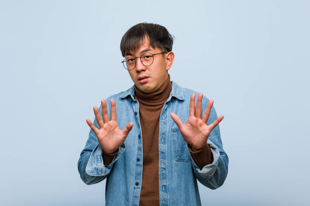 Młody chiński człowiek odrzucając coś robi gest wstrę - Zdjęcie, obraz