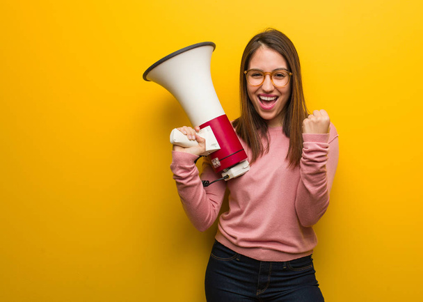 Young cute woman holding a megaphone surprised and shocked - Photo, Image
