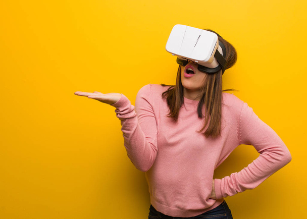 Young cute woman wearing a virtual reality googles holding something on palm hand - Photo, Image