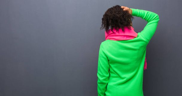 Νεαρή Αφροαμερικανή με μπλε μάτια από πίσω να σκέφτεται κάτι. - Φωτογραφία, εικόνα