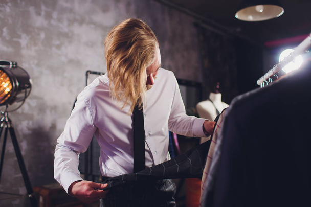 portrait of male client choosing classic jacket in the mall. - Fotó, kép