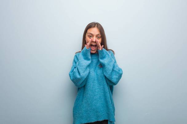 Joven mujer bonita con un suéter azul gritando algo feliz al frente
 - Foto, imagen