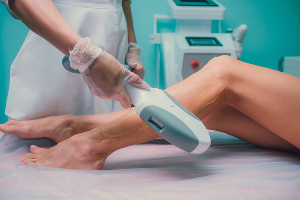 Hair removal cosmetology procedure from a therapist at cosmetic beauty spa clinic. Laser epilation and cosmetology. Teal orange. - Фото, зображення