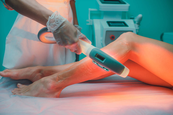 Hair removal cosmetology procedure from a therapist at cosmetic beauty spa clinic. Laser epilation and cosmetology. Teal orange. - 写真・画像