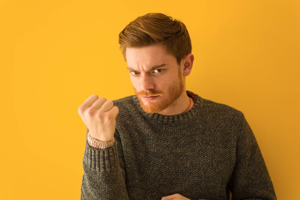 Young redhead man face closeup showing fist to front, angry expression - Photo, Image