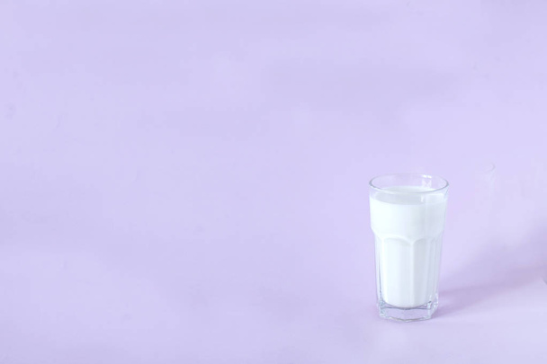 glass of fresh milk on a lavender background - Foto, Imagen