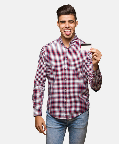 Jonge man met creditcard funnny en vriendelijke weergegeven: tong - Foto, afbeelding