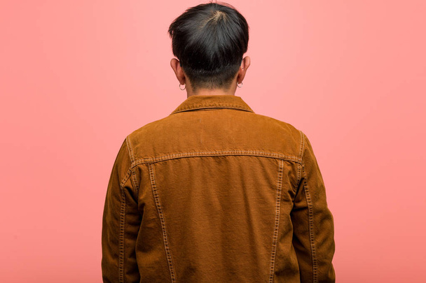 Jovem chinês vestindo um casaco por trás, olhando para trás
 - Foto, Imagem