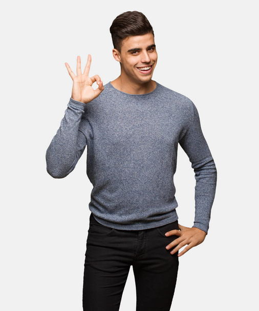 Young handsome man cheerful and confident doing ok gesture - Fotoğraf, Görsel