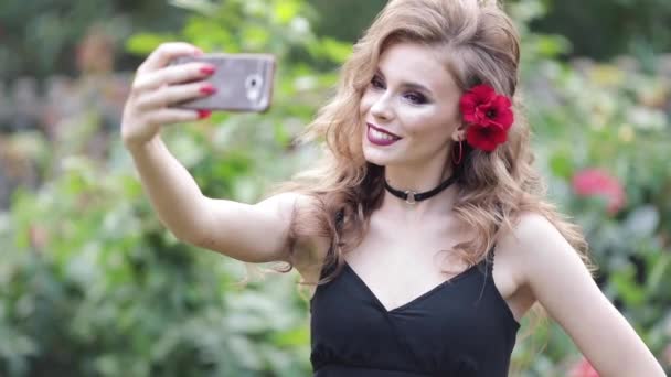 wunderschöne kaukasische Mädchen mit Frisur in sinnlichem Kleid macht Selfie im Garten. - Filmmaterial, Video