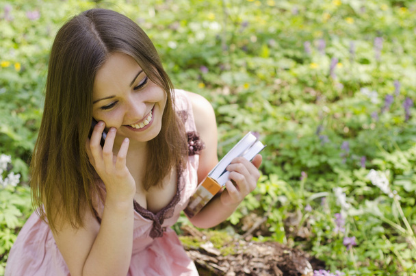 kitap ile güzel bir gülümseyen kız telefonda konuşuyor - Fotoğraf, Görsel