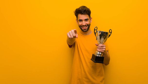 Young man holding a trophy cheerful and smiling - Photo, Image
