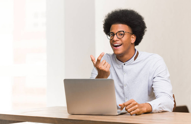 Молодой чёрный мужчина, используя свой ноутбук, приглашает прийти.
 - Фото, изображение