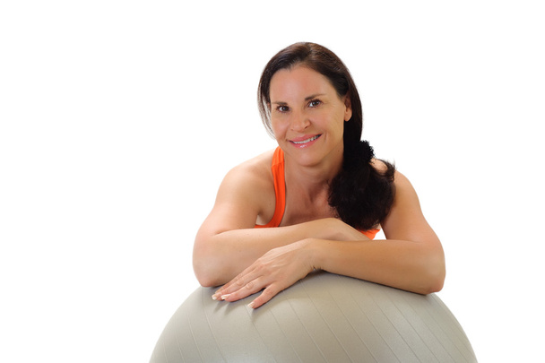 Mujer morena apoyada en una pelota de ejercicios de Pilates gris
. - Foto, Imagen
