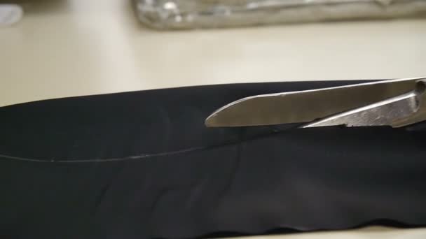 A dressmaker cutting a high quality fabric black, before you sew it and make a piece of high fashion clothing. The seamstress uses professional scissors . traditional concept, industry and fashion. - Footage, Video