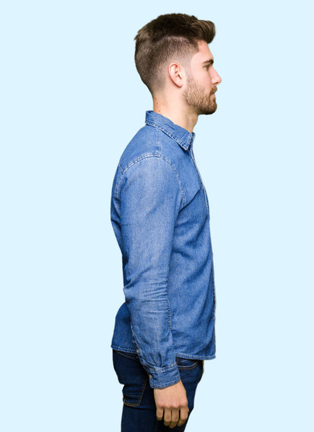 Young handsome blond man wearing casual denim shirt looking to side, relax profile pose with natural face with confident smile. - Fotoğraf, Görsel