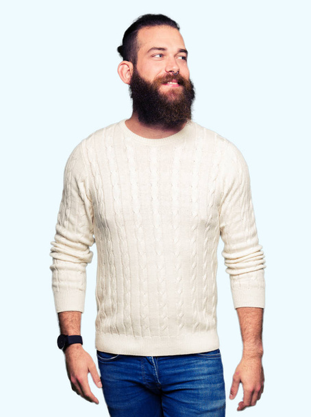 Young hipster man wearing winter sweater smiling looking side and staring away thinking. - Foto, Imagen