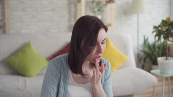Close up of a young woman smears chapped lips healing balm sitting - Video