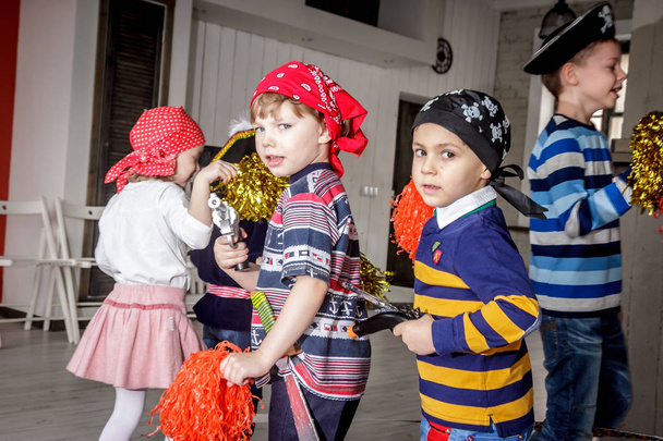 RUSSIA, YAROSLAVL - 17 FEB. 2018: happy group of children at a birthday celebration dressed in the style of pirates with an animator, contests and bubbles play games in a large room with loft style - Φωτογραφία, εικόνα