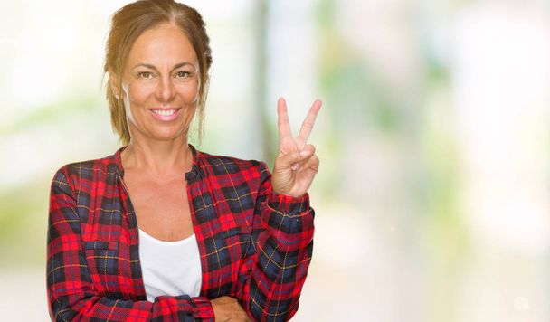 Middle age adult woman wearing casual jacket over isolated background smiling with happy face winking at the camera doing victory sign. Number two. - Photo, Image