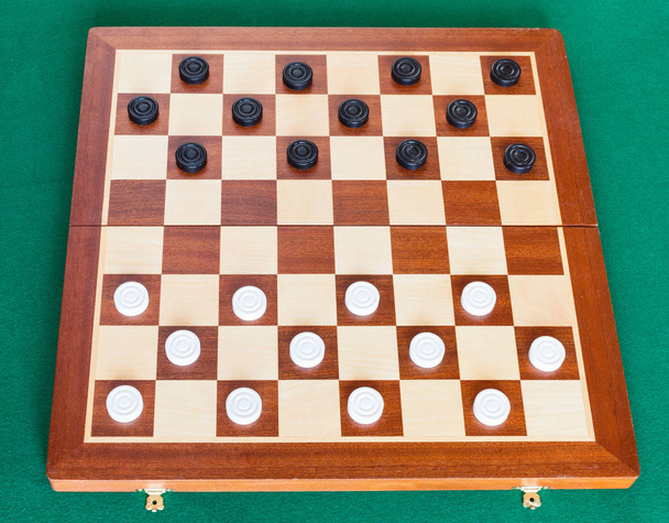 шашки на деревянной доске на зеленом столе
 - Фото, изображение